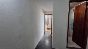 un couloir avec une porte et une chambre avec un miroir dans l'établissement Kitinet semi mobiliada ótima localização, à São Pedro da Aldeia