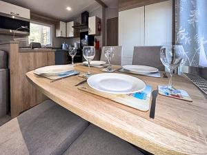a wooden table with plates and wine glasses on it at Unit 44 in Weybourne