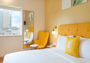 a hotel room with a bed and a yellow chair at Bloom Hotel Financial District in Hyderabad