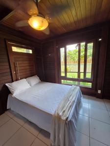 a bedroom with a white bed with a window at Casa da Karina in Arraial d'Ajuda