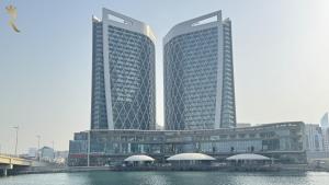 dwa wysokie budynki obok zbiornika wodnego w obiekcie Modern Studio in Al Maryah Vista - Walk to The Galleria Mall & Cleveland Clinic w Abu Zabi