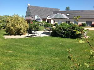 a yard with two chairs and a table and an umbrella at Les grandes Masures B&B in Varengeville-sur-Mer