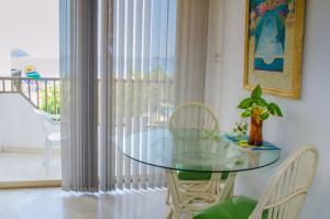 uma mesa de vidro e cadeiras num quarto com uma varanda em ENNA INN IXTAPA DEPARTAMENTO 01 RECAMARA ViSTA MAR em Ixtapa