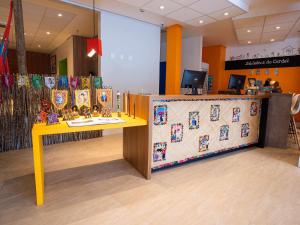 a store with a yellow counter with a table with toys at ibis Styles Campina Grande in Campina Grande