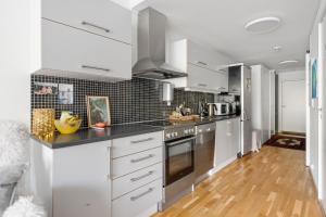 une cuisine avec des armoires blanches et des appareils en acier inoxydable dans l'établissement Costal Penthouse by Paramount, à Tromsø 3 autres photos