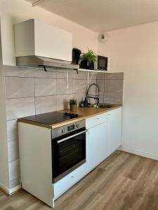 a kitchen with white cabinets and a stove top oven at Cozy apartment T1 in Bobigny