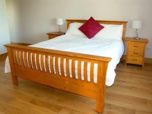 a large wooden bed with a red pillow on it at 4 Bed in Schull oc-ii09887 in Schull