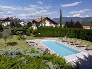 a swimming pool in a yard with chairs and a house at Stompferhof Familienapartment in Caldaro