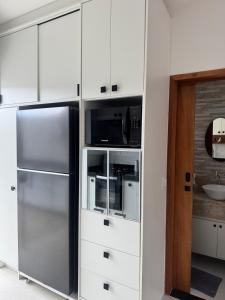 una cucina con armadi bianchi e frigorifero in acciaio inossidabile di Casa completa em Caraguatatuba - Rio do Ouro a Caraguatatuba