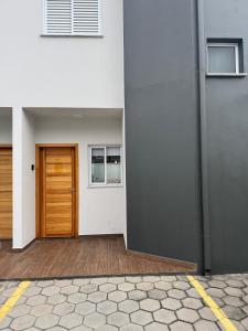 un edificio con una porta in legno e un edificio di Casa completa em Caraguatatuba - Rio do Ouro a Caraguatatuba