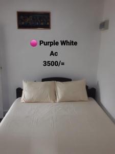 a white bed with a pink ball on the wall at Solamba Ella Mountain Resort in Bulatkohupitiya