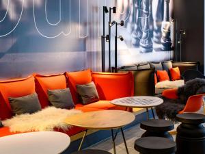 a living room with orange furniture and tables at ibis Regensburg Zentrum in Regensburg