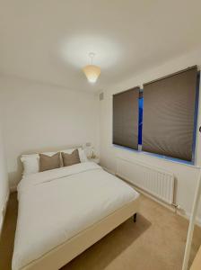 a white bedroom with a bed and two windows at Stockport Stays in Stockport +3 photos