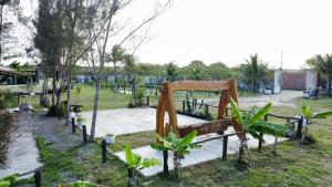 a park with a wooden bed in the grass at Casa Roar - Hospedagem in Nossa Senhora da Glória