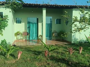 a house with green and white walls and a patio at Casa Roar - Hospedagem in Nossa Senhora da Glória
