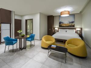 a hotel room with a bed and chairs and a table at Adagio Aparthotel Jeddah Malik Road in Jeddah