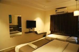 a hotel room with two beds and a television at Hotel Shirdi Park Inn 80 Meters From Sai Samadhi Temple in Shirdi