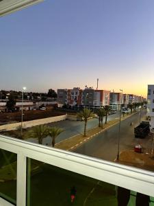 una ventana con vistas a una calle con palmeras en Réservez dès maintenant Calme confort et proximité, en Oulad Mbark