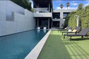 a swimming pool with chaise lounge chairs in front of a house at Beautiful palm tree villa in Marrakech