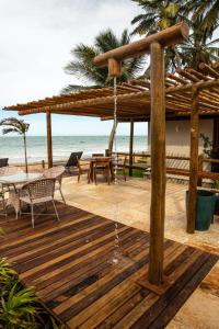 a wooden deck with a umbrella and a table and chairs at Vila Picos Icapui in Icapuí
