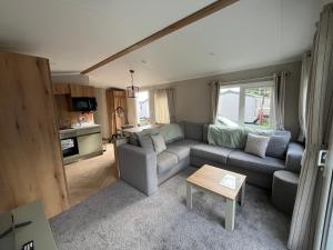 a living room with a couch and a table at The Orchards modern caravan in Saint Osyth