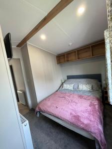a bedroom with a bed with a pink blanket at The Orchards modern caravan in Saint Osyth +11 photos