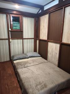 Cama en habitación con paredes y ventanas de madera en Sendang Seruni Guest House, en Jambu