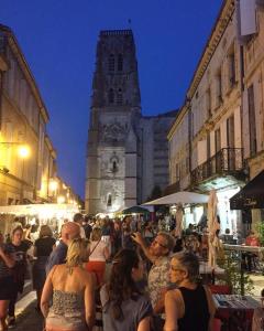 a crowd of people sitting in a street with a clock tower at La Maison du Vignoble piscine, tennis, Wallbox in Lectoure +54 photos