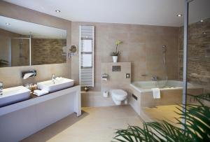 a bathroom with two sinks and a tub and a toilet at Fini-Resort Badenweiler in Badenweiler