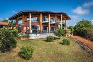 a large brick house with a balcony in a yard at SaffronStays Satori Hornbill, Ultra Luxe two bedroom Villa on 8 Acres Estate, By The Mulshi Lake in Mulshi
