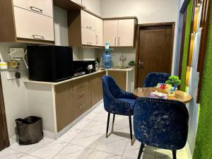a kitchen with blue chairs and a table and a tv at Beachfront Studios by Virani in Karachi