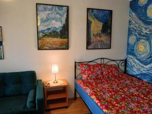 a bedroom with a bed and a couch and paintings at Meadow View 10 in Krakow