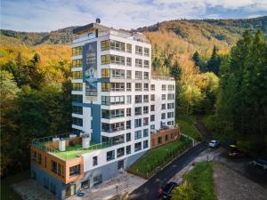 a tall white building in the middle of a forest at Kozubnik Apartment in Porąbka
