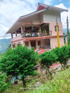 NamchiにあるDokhampa village Home stayの山の頂上にあるピンク色の家