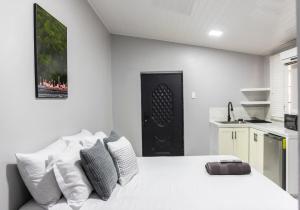 a white bedroom with a white bed and a kitchen at Tonys Guest House in Port-of-Spain
