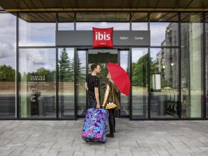 una mujer con un paraguas rojo y una mujer con una maleta en ibis Tallinn Center, en Tallin