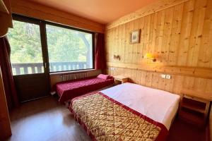 2 Betten in einem Zimmer mit Holzwänden und einem Fenster in der Unterkunft Second de Cordée in Combloux