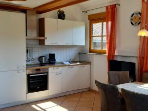 a small kitchen with white cabinets and a table at Schlosshof - Der Urlaubsbauernhof in Elzach