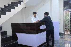 two men standing at a desk in a room with stairs at Shree Ramanam Palace in Ayodhya