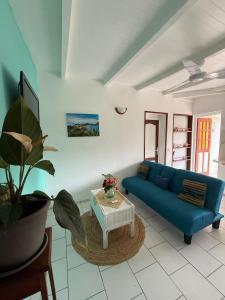 a living room with a blue couch and a table at Kaz à Zozio - F2 au calme à Bouillante in Bouillante
