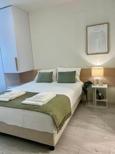 a bedroom with a large white bed with a green blanket at Casa dos Relevos - Centro Histórico de Santarém in Santarém