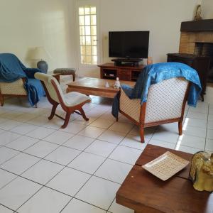 Una sala de estar con sillas, una mesa y un televisor. en Maison de plein pied et tranquille, en Sanguinet