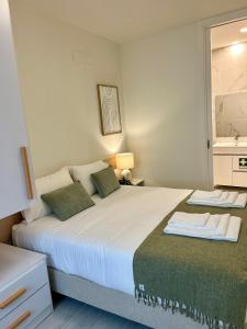 a bedroom with a large white bed with green pillows at Casa dos Relevos - Centro Histórico de Santarém in Santarém