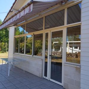 Un porche cubierto con una mesa y puertas de vidrio. en Maison de plein pied et tranquille, en Sanguinet