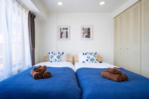 a bedroom with two beds with blue sheets and towels at ダイナスティパレス58 in Sapporo