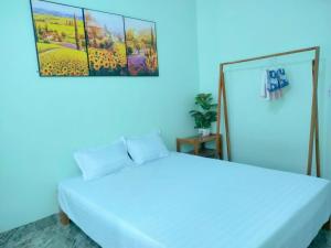 een slaapkamer met een wit bed en een blauwe muur bij Homestay Suối Mây Garden in Kon Rung (1)