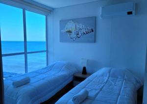 two beds in a room with a window at RESERVA DEL MAR - Playa Salguero - By INMOBILIARIA VS in Santa Marta