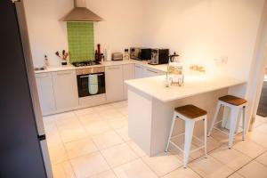 een keuken met witte kasten, een aanrecht en krukken bij Mountain Vineyard Cottage in Kaapstad +53 foto's