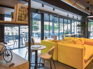 a restaurant with yellow chairs and tables and windows at ibis Styles Bâle-Mulhouse Aéroport in Blotzheim +43 photos