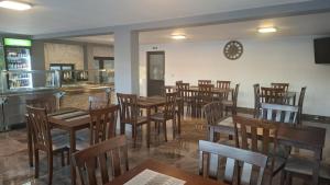 a restaurant with wooden tables and chairs and a clock on the wall at Casa Medeea in Podu Turcului +5 photos